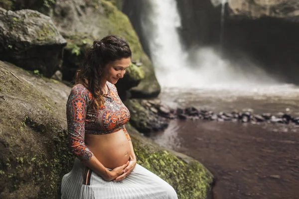 Junge authentische schwangere Frau in der Nähe von erstaunlichen Wasserfall. n — Stockfoto