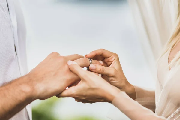 Bride putting wedding ring on groom's hand close up. Symbol of l — Stock Photo, Image