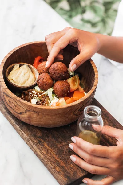 Wooden bowl with falafel balls, hummus and fresh salad. Woman ha — Stock Photo, Image
