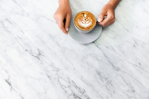 Copa de capuchino café fresco en las manos de la mujer en mármol blanco ta — Foto de Stock