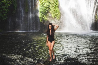 Kıvırcık saçlı, ince esmer kadın gölde eğleniyor. 