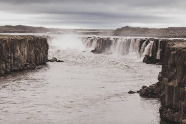 Soğuk ve gri sonbahar yorgunluğunda Selfoss şelalesinin dramatik manzarası