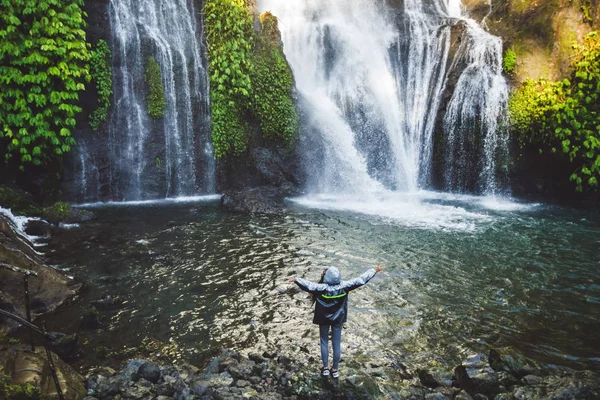 Jovem mulher feliz curtindo cachoeira em Bali. Vestindo chuva cinza — Fotografia de Stock