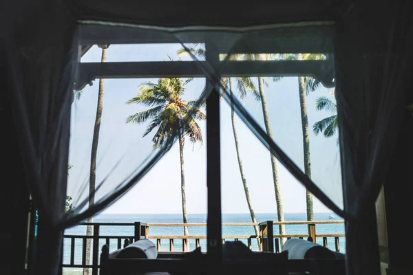 Tropikalny widok na ocean i palmę przez okno willi na Bali. — Zdjęcie stockowe
