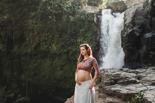 Young authentic pregnant woman near amazing cascade waterfall. N — Stock Photo, Image