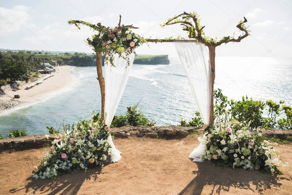 Sunset wedding ceremony arch with wooden branches and flower dec