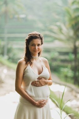 Bali pirinç terasları manzaralı beyaz elbiseli hamile bir kadın. Doğayla uyum. Hamilelik konsepti.