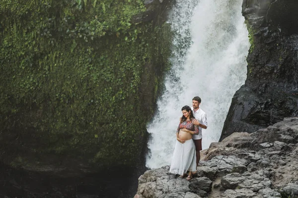 テゲヌンガン滝の素晴らしい景色を望む若い妊娠中のカップル 朝の日差し 幸せな一緒に 妊娠旅行生活 — ストック写真