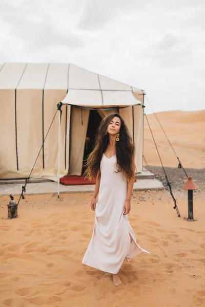 白いドレスで美しい東洋の若いブルネットの女性の肖像画 モロッコの砂漠でテントをグラミング モロッコの高級現代キャンプ — ストック写真