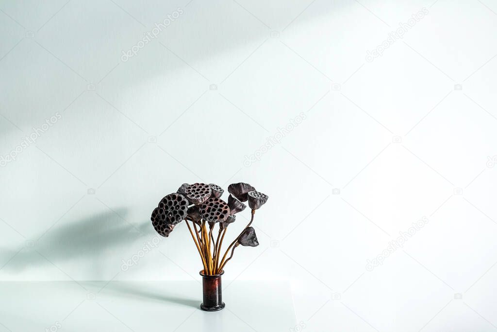 Flower pot with dried lily on white table background.  Minimal style in interior decoration. Contemporary concept. Beautiful sun light. Empty place for text or sign.