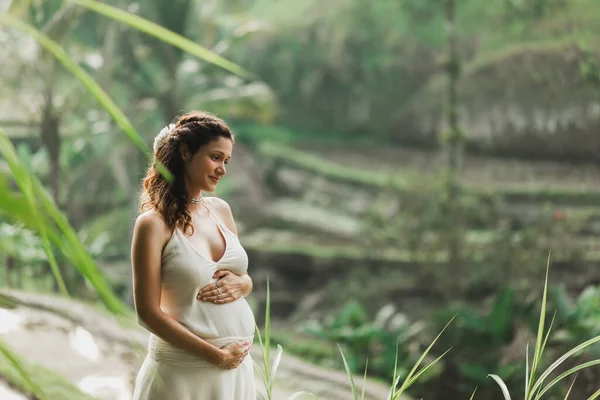 朝の日差しの中でバリの棚田を眺めながら白いドレスを着た若い妊婦 自然との調和 妊娠概念 — ストック写真