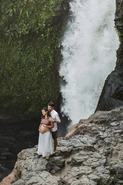テゲヌンガン滝の素晴らしい景色を望む若い妊娠中のカップル 朝の日差し 幸せな一緒に 妊娠旅行生活 — ストック写真