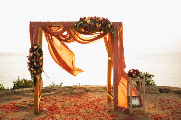屋外の日没の結婚式の広場木製の結婚式のアーチ 赤いバラの花やぶら下げ布 暖かい太陽の光 — ストック写真