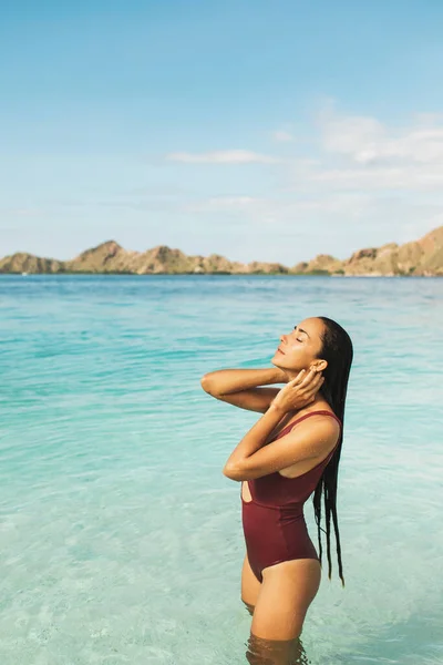 身穿红色泳衣的女人在清澈碧绿的海水中欣赏高山美景 旅行和度假概念 美丽与健康 带空隙的热带背景 — 图库照片