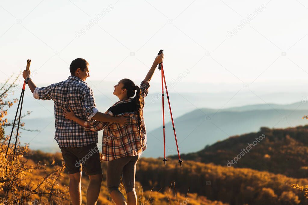 Couple happy together to hike top of mountain and hold trekking sticks.  Amazing autumn view. Travel lifestyle. Success goal achievement.