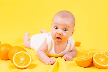 erkek bebek bir sarı portakal ile yatıyor.