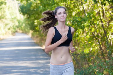 Kız egzersiz spor koşu bir orman yoluyla çalışır