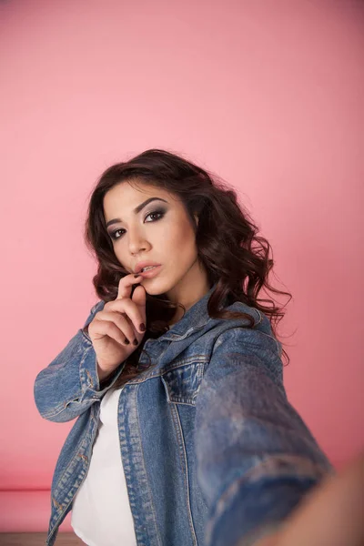 Chica en chaqueta de mezclilla hacer foto en el teléfono rosa — Foto de Stock