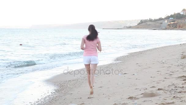 Chica por la mañana corre a lo largo de la playa cerca del mar — Vídeo de stock