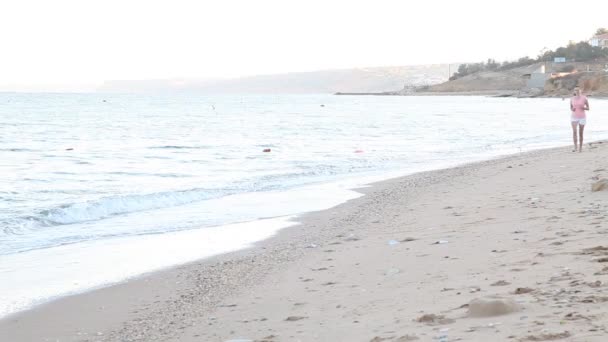 Flicka på morgonen går längs stranden nära havet — Stockvideo