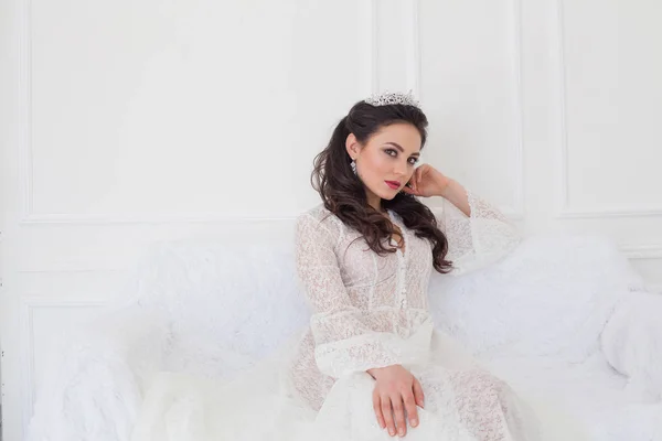 Невеста в свадебном платье сидит на диване — стоковое фото