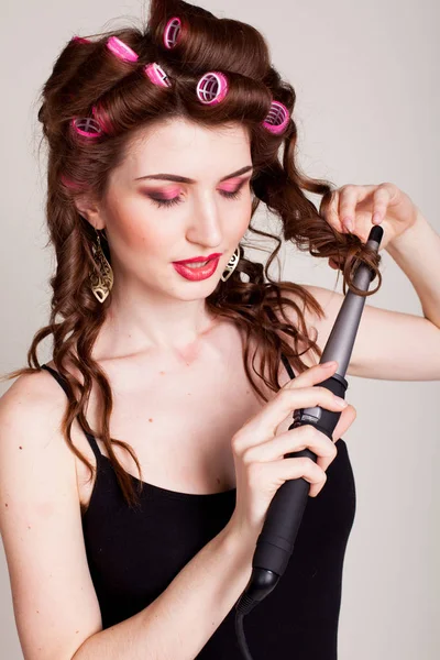 the girl with the curling Tong curler makes hairstyle