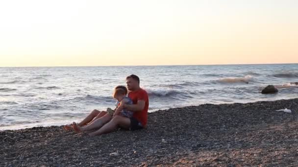Papai com dois meninos sentados em uma praia com filhos mar — Vídeo de Stock