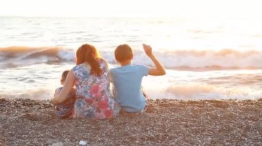 Anne ile oğlu deniz ile bir plaj gün batımında oturan iki çocuk
