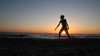 iki erkek plajda denize taş atan silueti