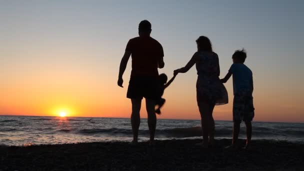 Silhouette familiare al tramonto vicino al mare mamma papà Bambini — Video Stock