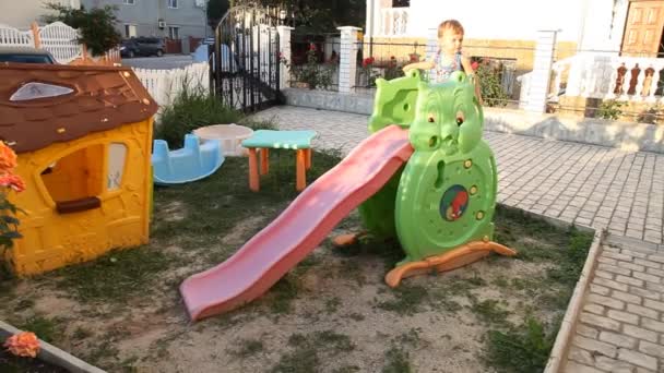 O menino brincando no playground desliza de uma colina — Vídeo de Stock