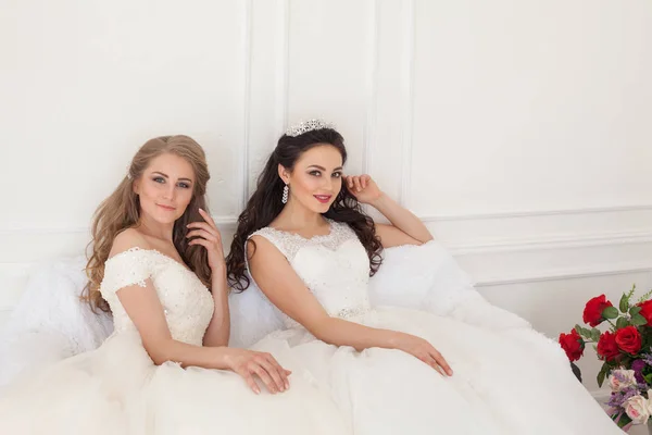 Portrét dvou mladých žen v svatební šaty v bílé hale — Stock fotografie