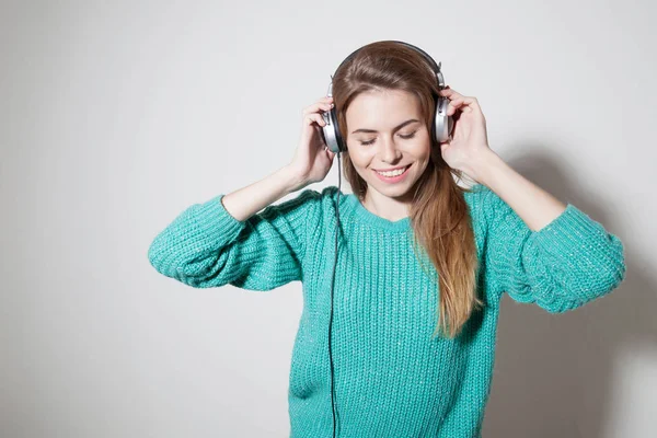 Mooi meisje luistert naar muziek in een koptelefoon — Stockfoto