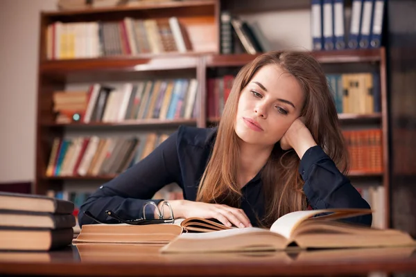 Ragazza studente si siede in biblioteca lettura — Foto Stock