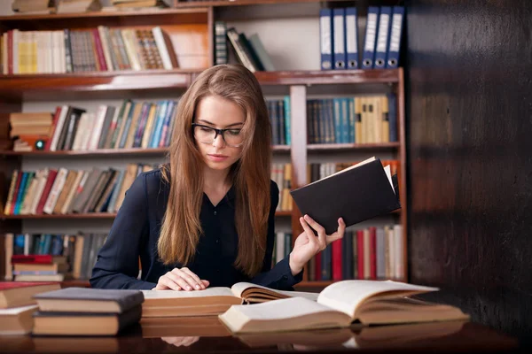 Ragazza studente si siede in biblioteca lettura — Foto Stock