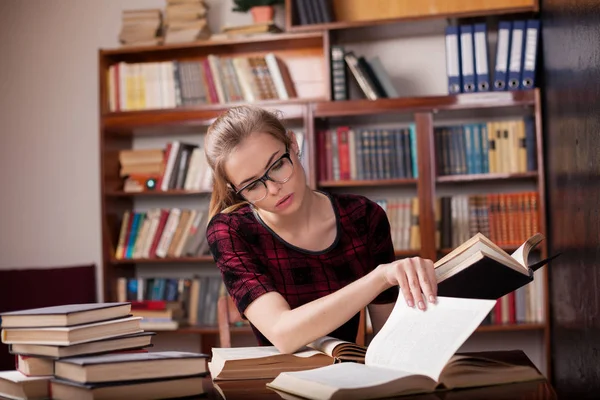 Chica estudiante se sienta en la biblioteca leyendo — Foto de Stock