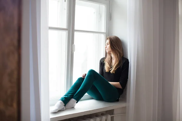 pencerenin yanında oturan kız caddeyi izliyor