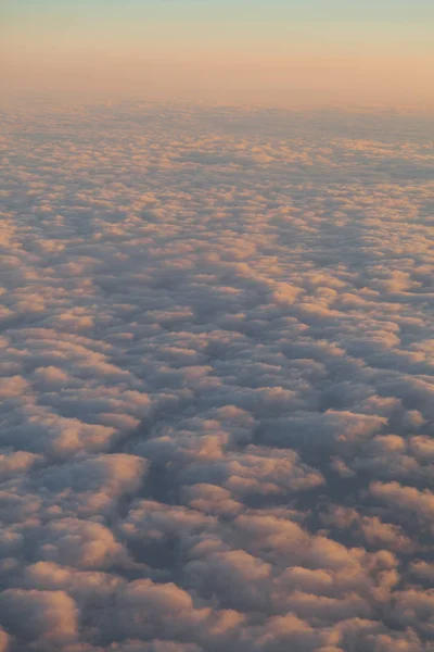 Sobrevolando las nubes al atardecer desde un avión — Foto de Stock