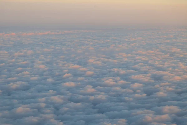 Sobrevolando las nubes al atardecer desde un avión — Foto de Stock