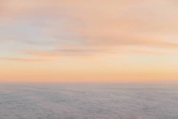 flying above the clouds at sunset landscape from an airplane