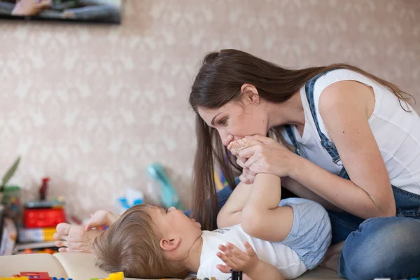 Mom plays with a little boy with love kisses laughs — Stock Photo, Image