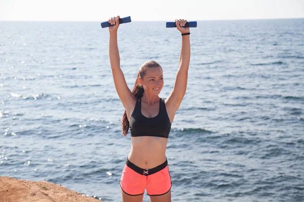 Girl Sports Fitness with dumbbells on the beach — Stock Photo, Image