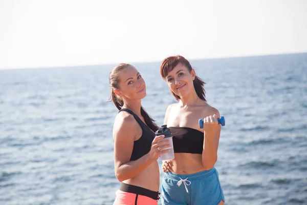 Chicas de fitness con coctelera y pesas en la playa — Foto de Stock