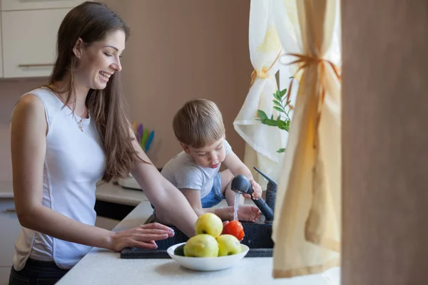 Кухня мама син миє фрукти та овочі — стокове фото