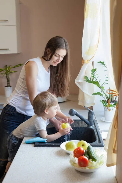 The little boy is helping mom in the kitchen — Stock Photo, Image
