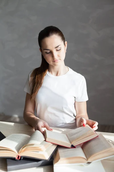 Chica trabaja en el ordenador lee un libro en la biblioteca — Foto de Stock