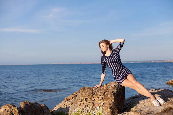 Meisje zit op de rotsachtige strand geniet van zon — Stockfoto