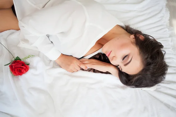 Chica en lencería acostada en una cama con una rosa —  Fotos de Stock