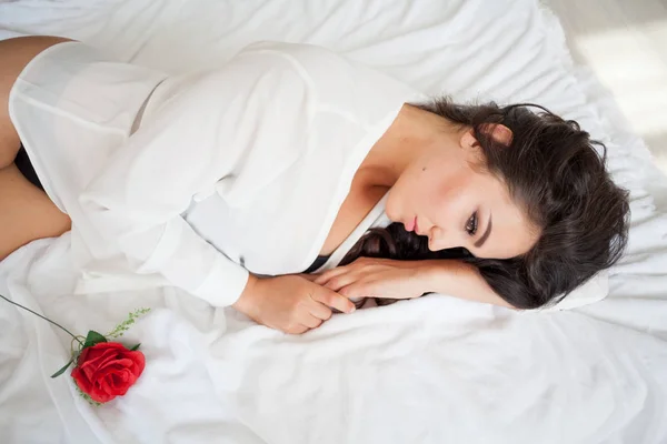 Chica en lencería acostada en una cama con una rosa — Foto de Stock