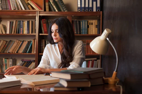 Girl is preparing for the exam reading book at the library — Stock Photo, Image